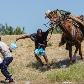 Un agente de la patrulla fronteriza de Estados Unidos a caballo intenta detener a dos migrantes haitianos en el río Grande (Texas).