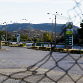 En primer plano, una valla rota. Al fondo, una gasolinera en Evzoni. - Cedida