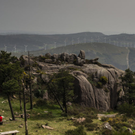 Una familia come en el área recreativa del Monte Pindo, con los molinos al fondo en las montañas.