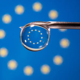 La bandera de la UE se refleja en la gota de una jeringuilla.