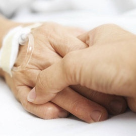 Una persona coge la mano a un paciente.