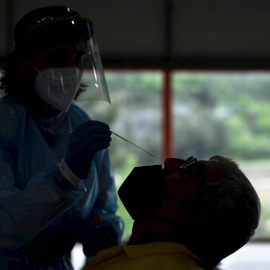 Una trabajadora sanitaria realiza una prueba PCR a un hombre, durante el cribado realizado este lunes a la población de Sobradelo (Carballeda de Valdeorras).