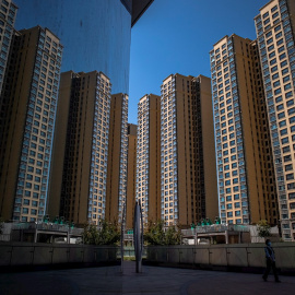 Una mujer camina cerca de bloques de edificios de apartamentos levantados por la inmobiliaria Evergrande, en Pekín. EFE/ROMAN PILIPEY