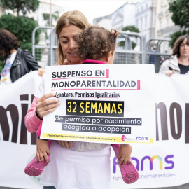 Una mujer sostiene a su hija en brazos durante una concentración de madres solteras, en el Congreso de los Diputados, a 29 de septiembre de 2022, en Madrid.