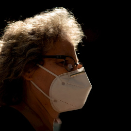 Una mujer camina por una calle de Barcelona con mascarilla.