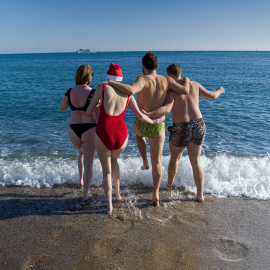 Unos jóvenes se bañan en la playa de la Barceloneta, a 25 de diciembre de 2022, en Barcelona.