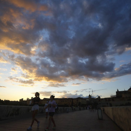 Varias personas caminan sobre el puente romano en Córdoba.