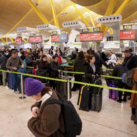 viajeros hacen cola ante los mostradores de 'check-in' de las compañías aéreas este viernes en el aeropuerto de Madrid Barajas.