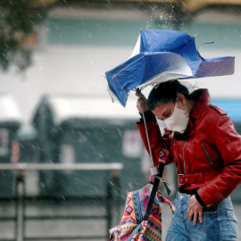 Una persona trata de protegerse de la intensa lluvia.