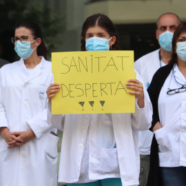 Una enfermera con una pancarta defendiendo la salud pública durante una movilización ante la Delegación de la Generalitat a Girona. ACN/Aleix Freixas