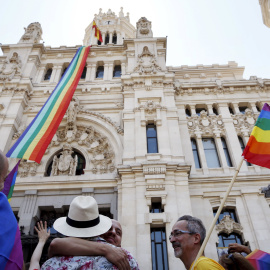 Una bandera con los colores del arco iris, símbolo LGTB, ondea en el Ayuntamiento de Madrid mientras algunas parejas homosexuales lo celebran en los aledaños del consistorio. REUTERS