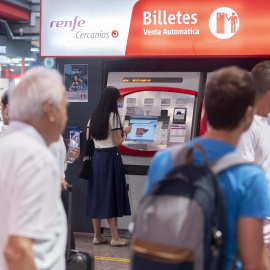 Varias personas adquieren sus billetes en las taquillas de venta automática de la estación de tren de Atocha.