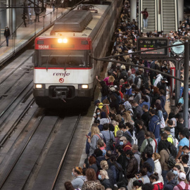 Un gran número de pasajeros espera la llegada de un tren en la estación de Madrid.
