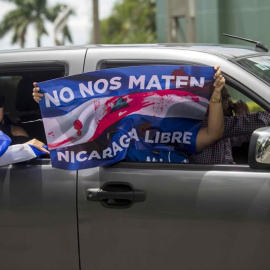 04/07/2018.- Un grupo de personas agita una bandera desde un vehículo durante un plantón denominado "Cadena Humana de Rotonda a Rotonda", a una distancia 3.4 km en la carretera hacia Masaya, hoy, miércoles 4 de julio de 2018, en Managua (Nicaragua). De