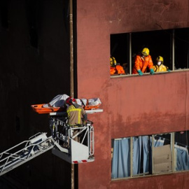 Bomberos retiran el cadáver de una de las personas fallecidas en el incendio de ayer en la nave okupada del barrio de Gorg, en Badalona, Barcelona, Catalunya