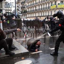 Un agente de policía francés echa spray sobre un manifestante en el suelo.