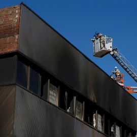 Bomberos de la Generalitat de Catalunya y trabajadores de la empresa de derribos inspeccionan este sábado en Badalona el inicio de la demolición de la nave donde murieron tres inmigrantes "sin techo" en un incendio. La nave, una antigua fábrica en desu