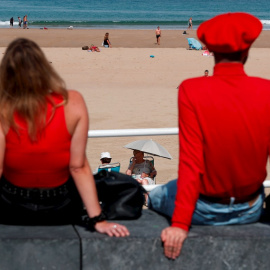 Dos personas disfrutan de las vistas de la playa en San Sebastián.
