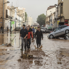 Varias personas recorren calles llenas de agua y barro tras el paso de la DANA por el barrio de La Torre de València, a 30 de octubre de 2024.