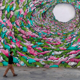 Un vecino del municipio murciano de Torre Pacheco pasea junto a un grafiti.