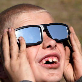 Un niño con unas gafas de sol especiales para observar el eclipse de Sol. REUTERS/Rick Wilking