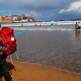 Una mujer pasea por la playa de San Lorenzo de Gijón.