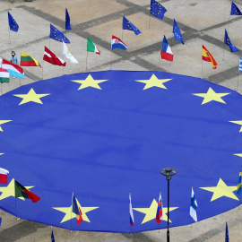 Una enorme bandera de la Unión Europea, rodeada junto a otras de los diferentes países comunitarios, aparece desplegada en la Plaza Schuman, frente a la sede de la Comisión Europea, en Bruselas, con motivo del Día de Europa. REUTERS/Yves Herman