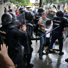 Un hombre intenta proteger a una mujer de los porrazos de agentes antidisturbios de la policía española el 1 de octubre de 2017.