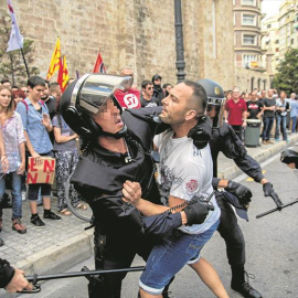 La policía forcejea con uno de los agresores durante la manifestación del 9-O en Valencia. - EFE