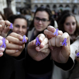 Varias jóvenes muestran lazos de color violeta, que simbolizan la lucha contra la violencia machista. (EFE)