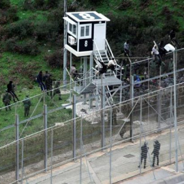 Varias personas migrantes intentan superar la valla fronteriza entre Ceuta y Marruecos, en una imagen de diciembre de 2017.-EFE