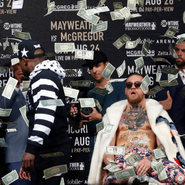 Mayweather arroja un fajo de billetes a la cara de McGregor durante uno de los careos para la promoción del combate.REUTERS/Noah K.Murray