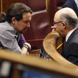 El ministro de Hacienda, Cristóbal Montoro, conversa con el líder de Podemos, Pablo Iglesias, durante un Pleno del  Congreso de los Diputados. EFE/Javier Lizón