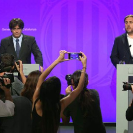 El presidente de la Generalitat de Cataluña Carles Puigdemont(i), y el vicepresidente del Govern y Conseller de Economía, Oriol Junqueras(d), comparecen ante los medios de comunicación en el Palau de la Generalitat para anunciar las medidas del Tribuna