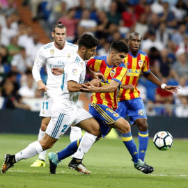 El delantero del Real Madrid Marco Asensio lucha el balón con Carlos Soler, del Valencia CF. - EFE