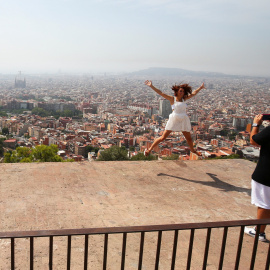 Una joven turista salta,mientras le toman una foto con el 'skyline' de Barcelona a su fondo. REUTERS/Albert Gea