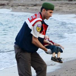 Un agente turco recoge el cadáver de Aylan. - REUTERS