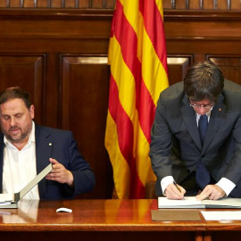 El presidente de la Generalitat, Carles Puigdemont, acompañado por el vicepresidente Oriol Junqueras, firma la convocatoria de referéndum. - EFE