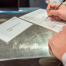 Una persona rellena unos documentos tras solicitar el voto por correo, en Madrid a 14 de junio de 2023