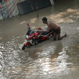 13/07/2023.- Un hombre empuja su moto en una zona inundada cerca del río Yamuna en Nueva Delhi, India, 13 de julio de 2023.