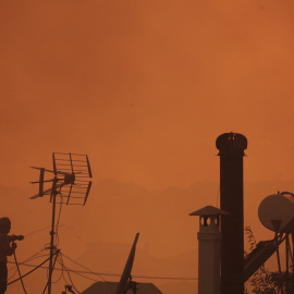 Un hombre rocía agua desde la azotea de su casa durante un incendio forestal en el área de Lagonisi en Ática, Grecia, el 17 de julio de 2023.