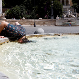 Una mujer sumerge su cabeza en el agua de la Piazza del Popolo, en Roma, para hacer frente al calor extremo que sacude a Italia.