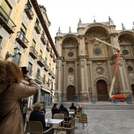 Varios operarios, subido a una grúa , revisan la fachada de la Catedral de Granada. Archivo.