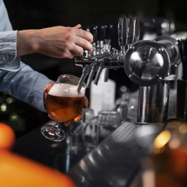 primer plano mano vertiendo cerveza en vidrio