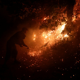 Un vecino intenta apagar las llamas cerca de Vigo.- REUTERS