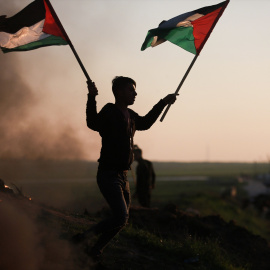 Un manifestante con la bandera de Palestina en la frontera de Gaza protesta tras los últimos ataques contra un campamento de refugiados en Yenín.