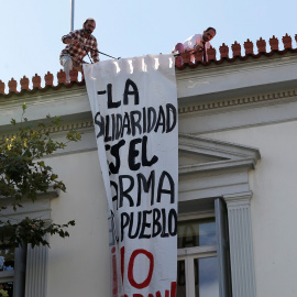 Empleados de la embajada española en Atenas retiran la pancarta "La solidaridad es el arma del pueblo". /REUTERS