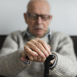 Vista frontal de una persona mayor con un bastón en una residencia (archivo)