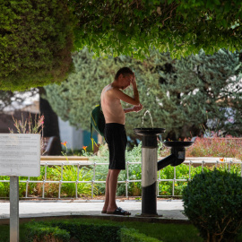 Varios vecinos se refrescan en una fuente en la plaza del Altozano, a 10 de agosto de 2023, en Albacete, Castilla-La Mancha (España).