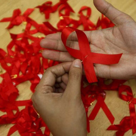 Una joven prepara lazos rojos durante una campaña de concienciación sobre la prevención del contagio del sida. - EFE